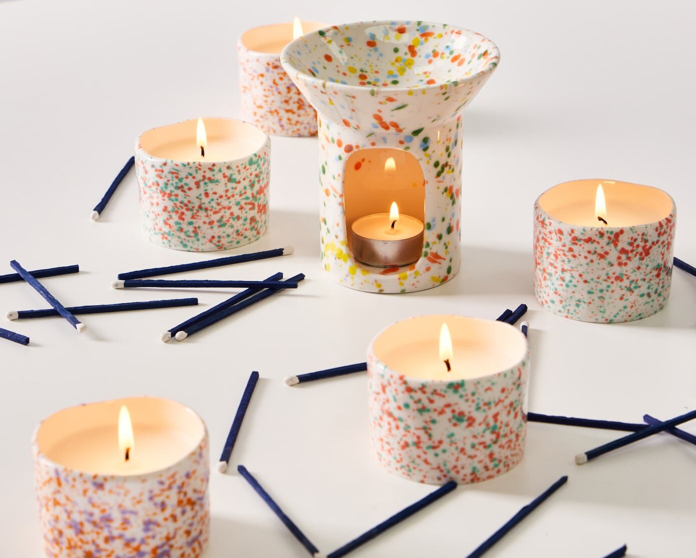 A group of ceramic splatter scented candles and matches 