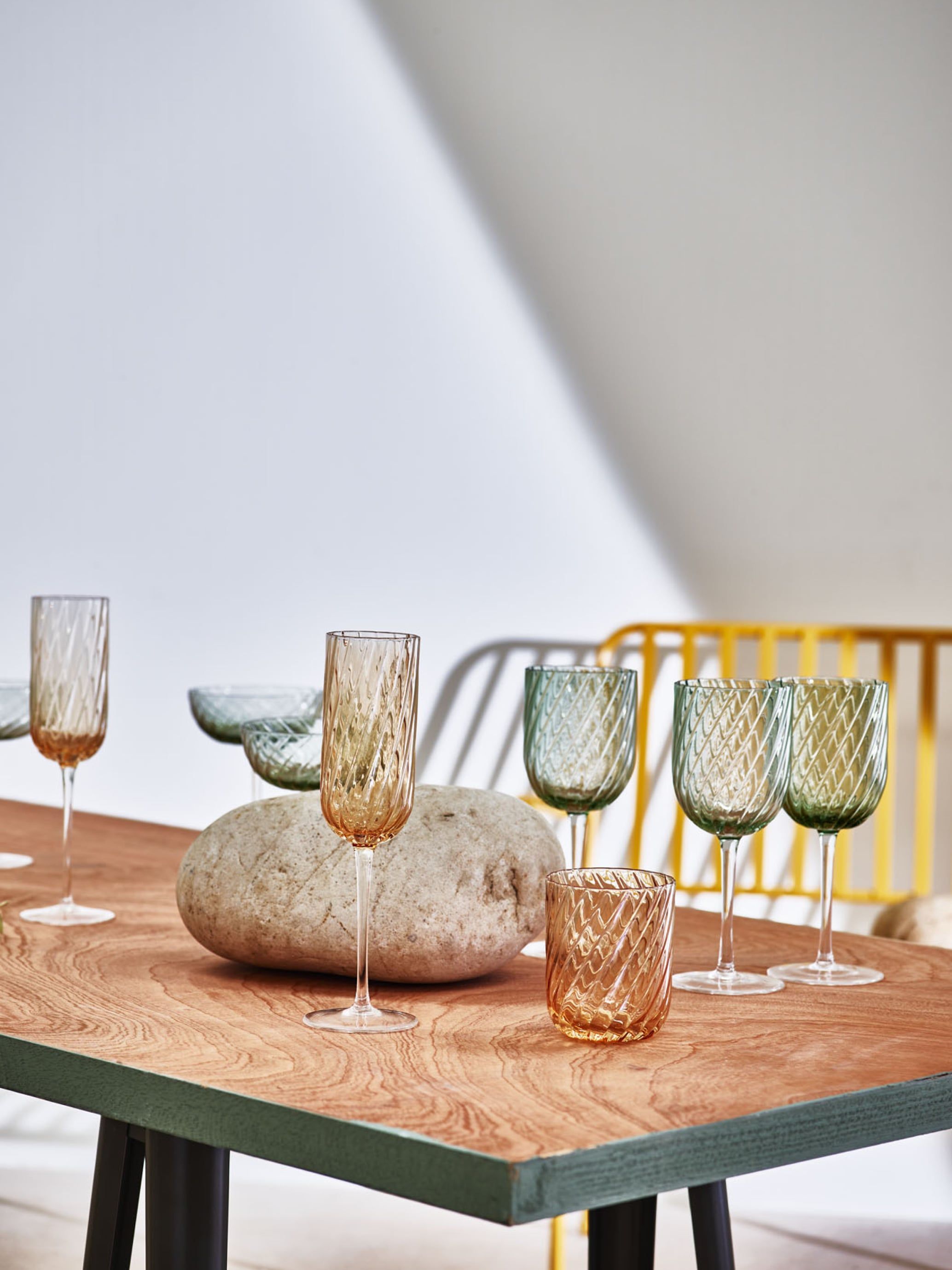 Green and yellow drinking glasses on a wooden table 