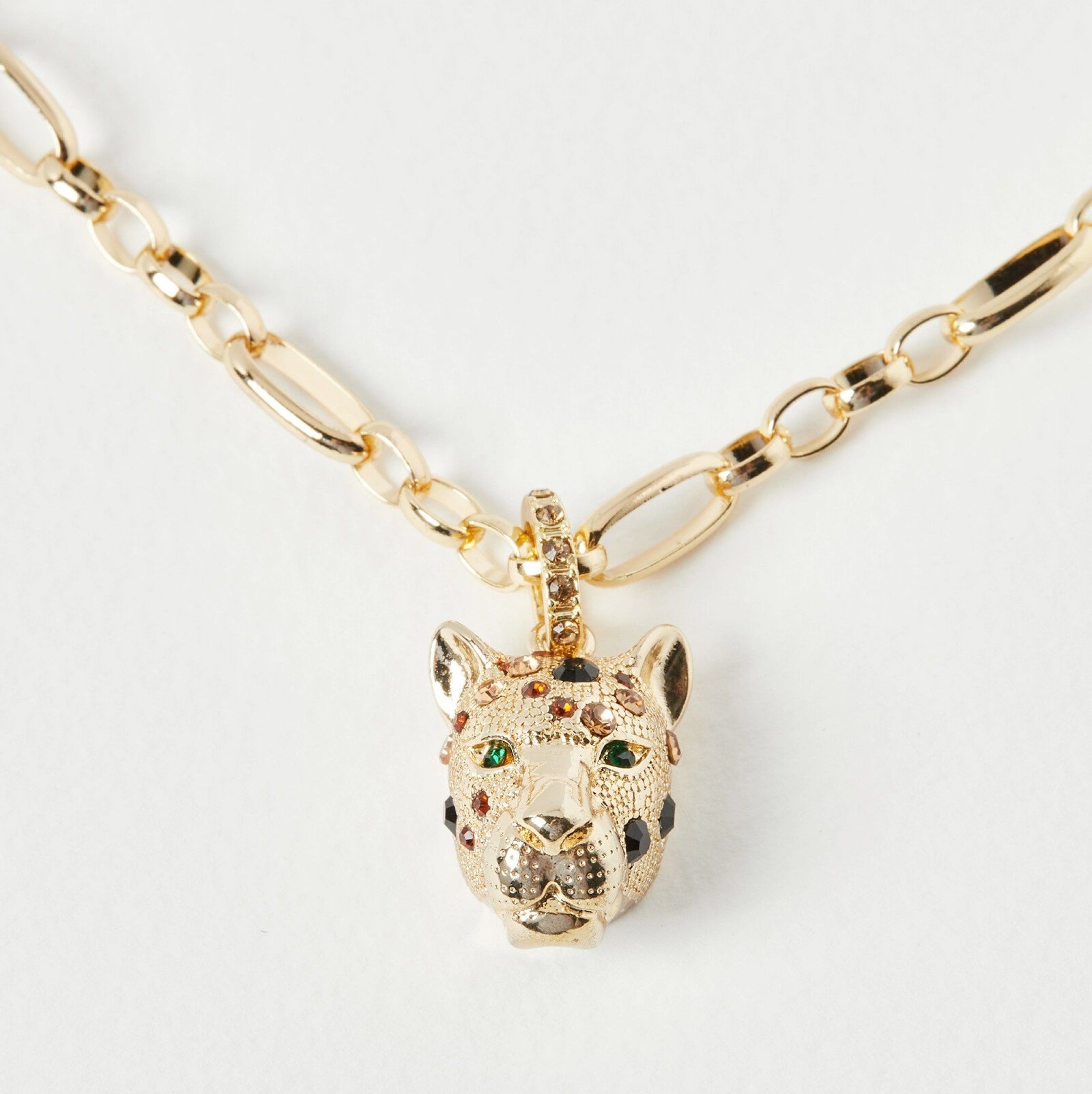 A gold figaro chain necklace with a cheetah pendant