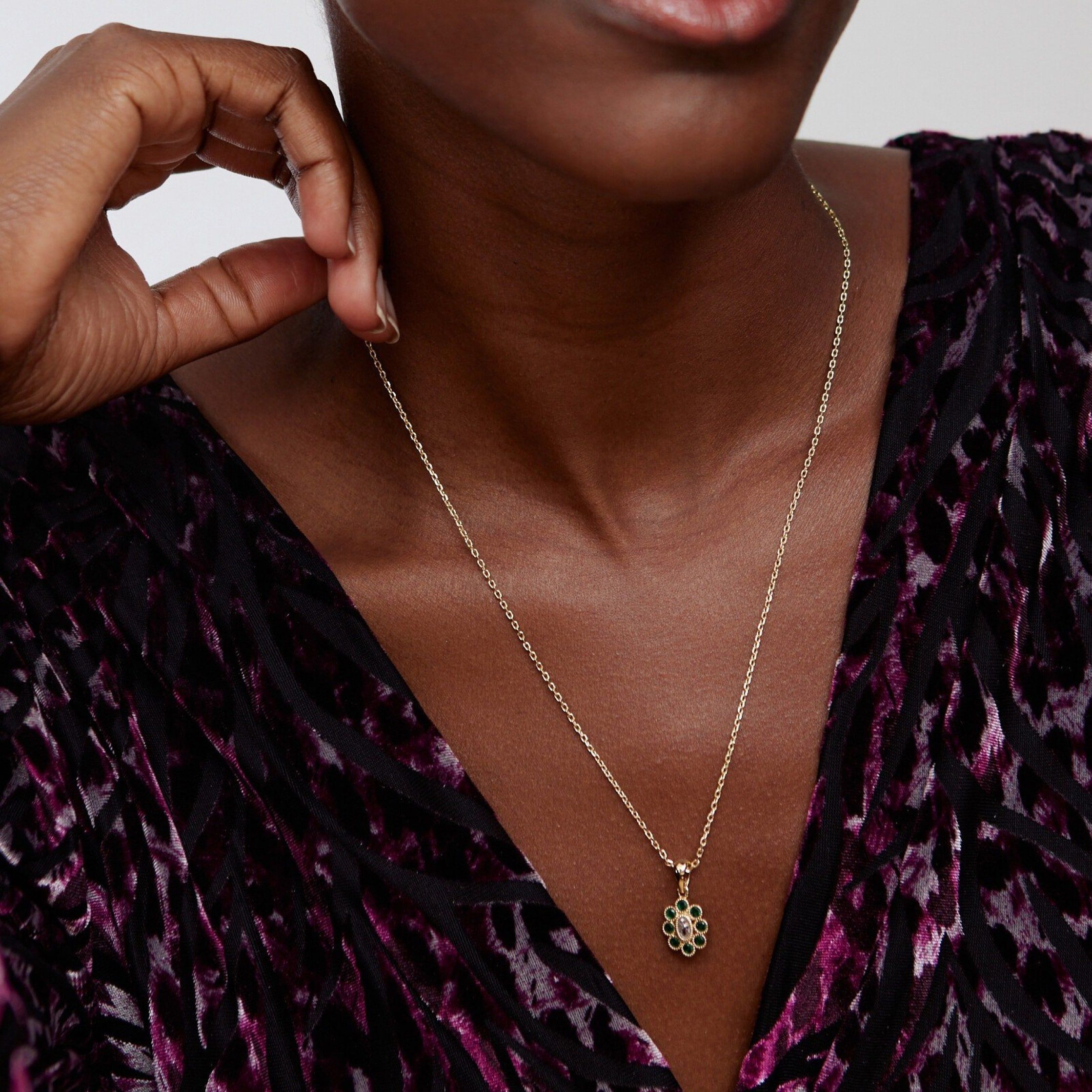 model wearing a gold toned cable chain with a green flower pendant 