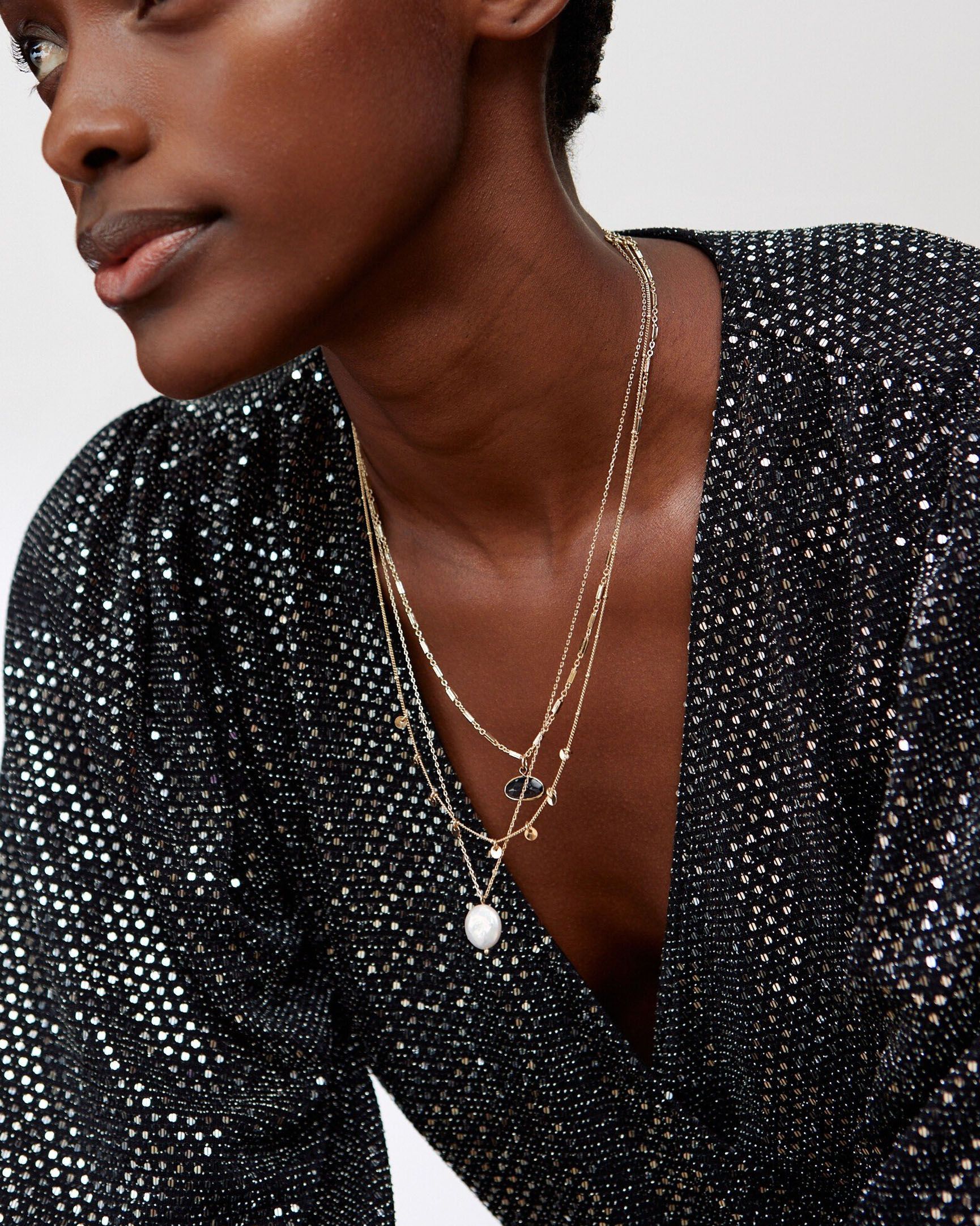 Model wearing a sparkly black dress and layered necklace 